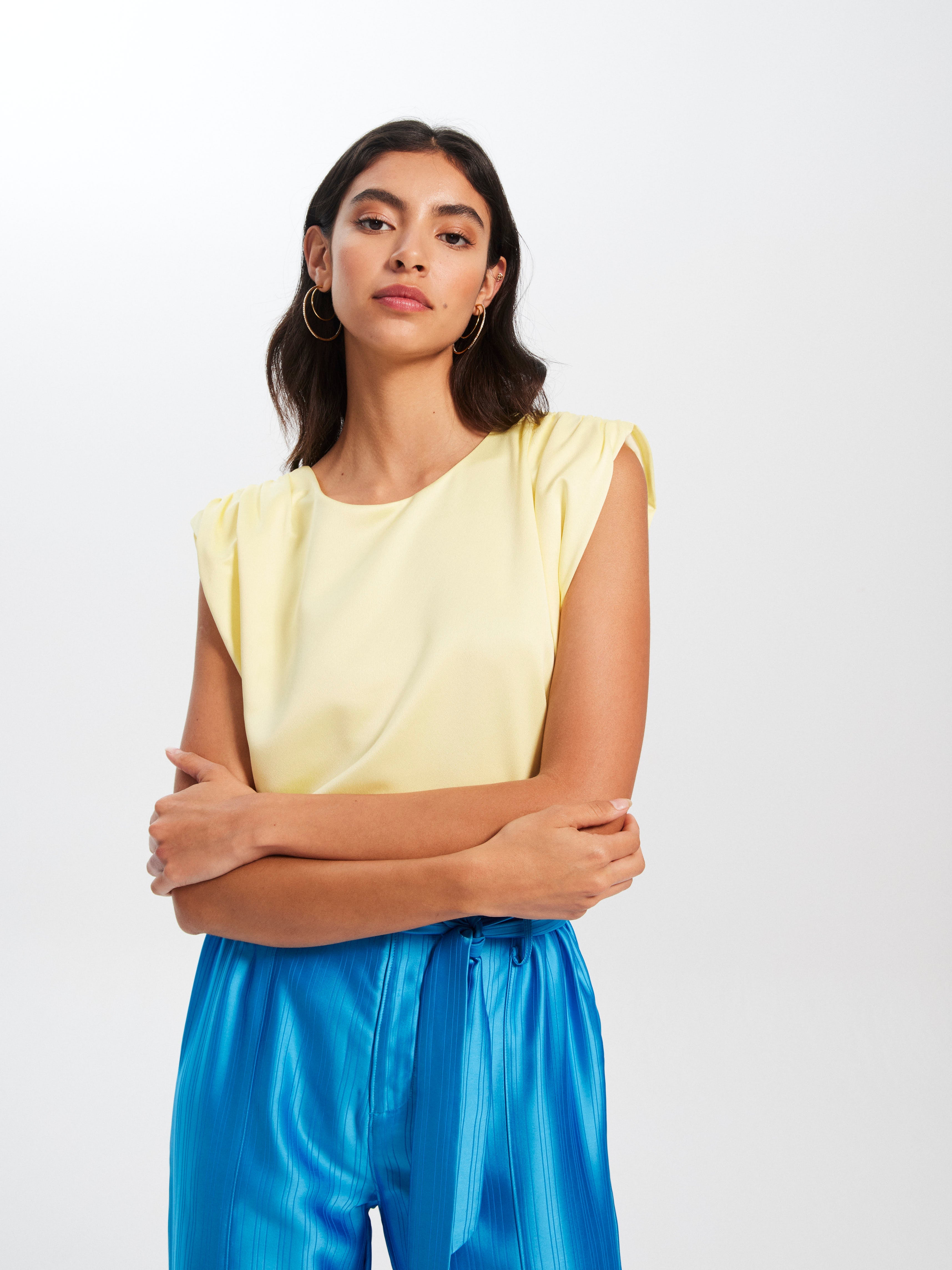 mioh | MARIA - Nuestro top de fiesta sin mangas en color amarillo para ser la invitada de boda perfecta esta temporada Primavera Verano 2023. Los tops son perfectos para hacer un look de invitada fácil, combinables con falda, pantalón o traje. Son pura tendencia SS23. Mioh es la marca española más de moda de vestidos de invitada.